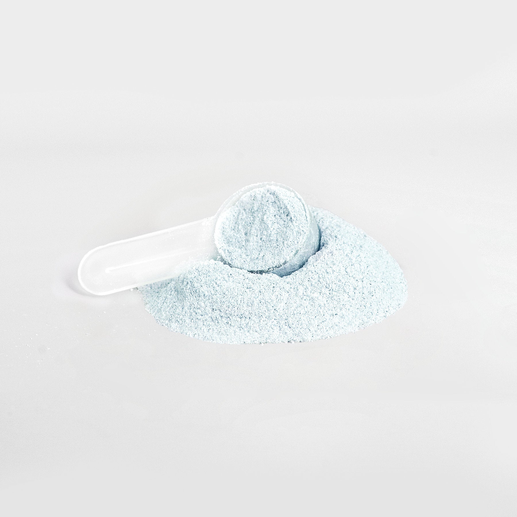 Close-up image of HYDRATE Hydration Powder by Peak Rugby, showing a clear scoop filled with light blue electrolyte powder on a white surface.