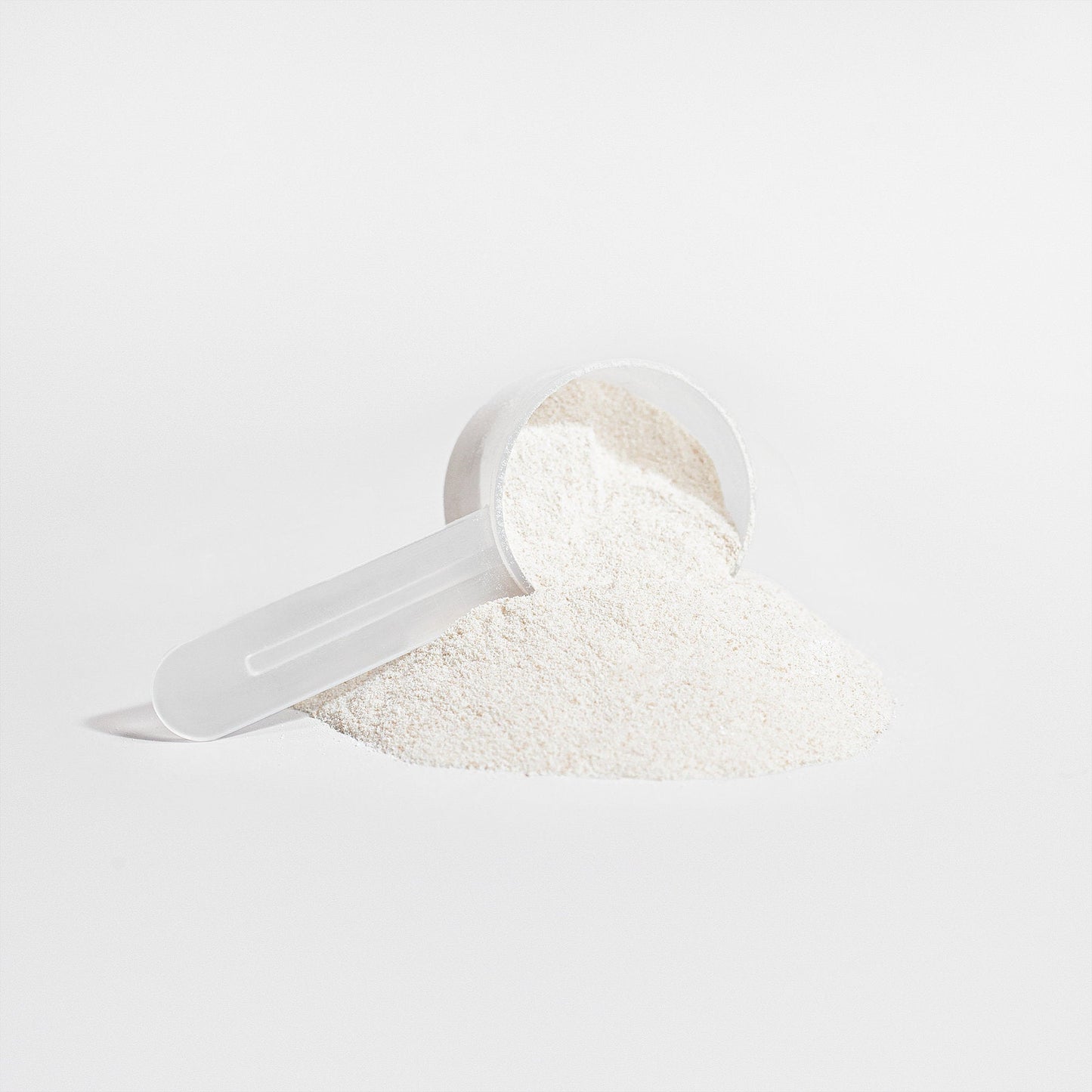 Close-up of a scoop filled with PROTECT Grass-Fed Collagen Peptides powder by PEAK RUGBY. The fine white powder is displayed on a clean white background, highlighting its texture.