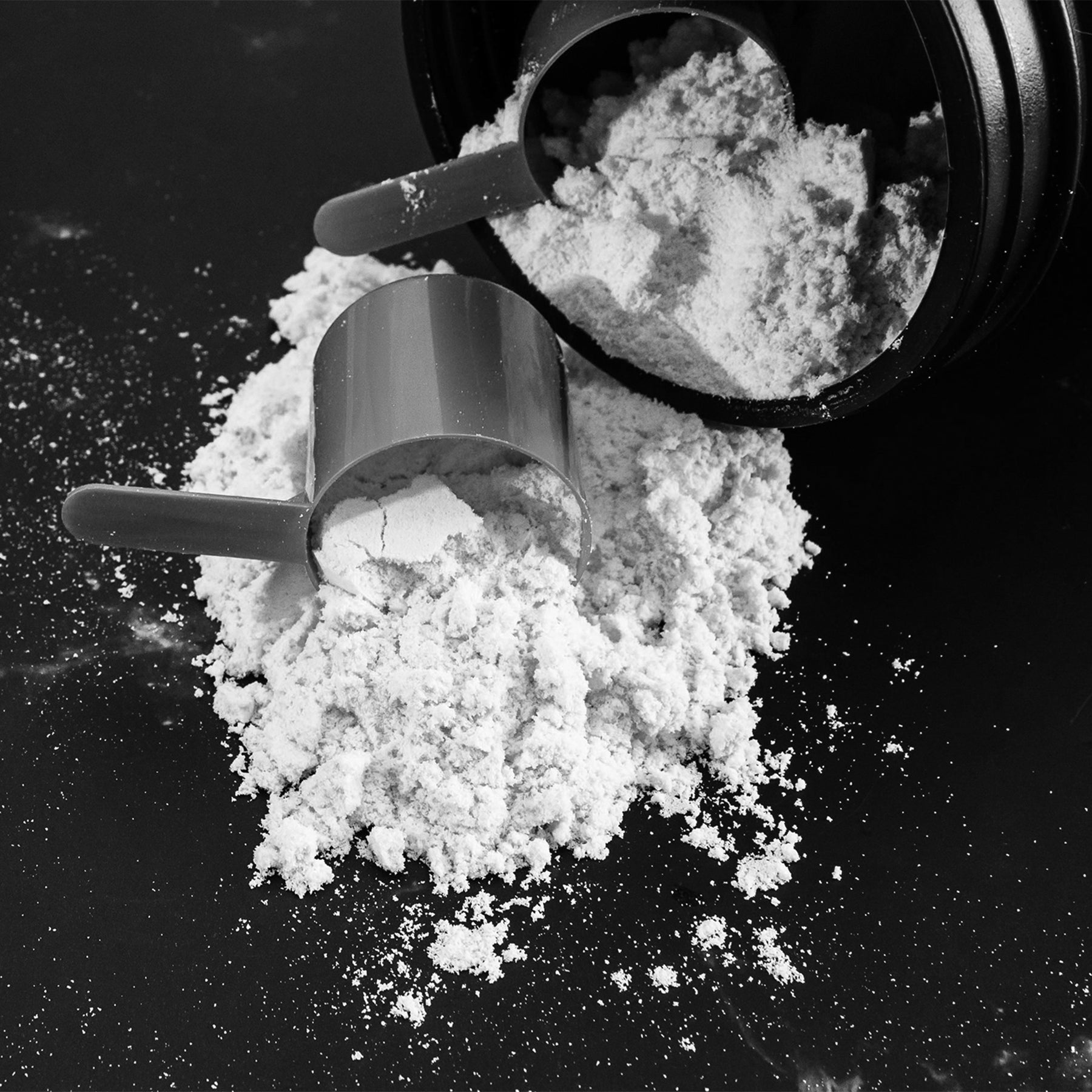 Black and white mobile banner image for Peak Rugby supplements shop page, featuring protein powder spilling from a container with scoops on a dark surface.